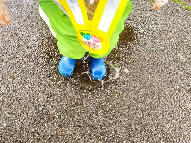 Kind in Regenkleidung und Gummistiefeln bei einer Outdoor-Aktivität der Kita Bärlis